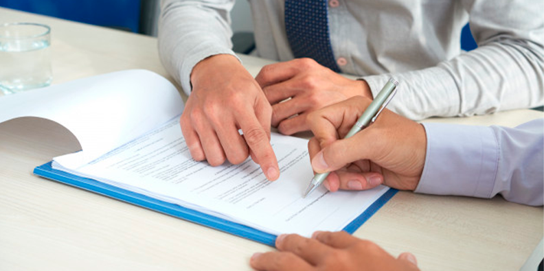 Imagem de um contrato e uma pessoa assinando o documento.