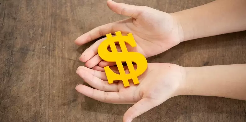 The yellow dollar symbol on hands children Imagem de uma pessoa segurando um cifrão de cor amarela