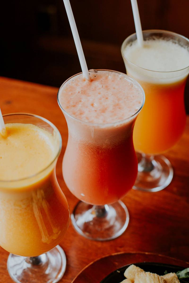 Mulher segurando um copo de suco de tangerina e preparando um smoothie de tangerina em casa