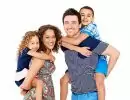 Portrait of playful young parents giving piggyback ride to children on white background